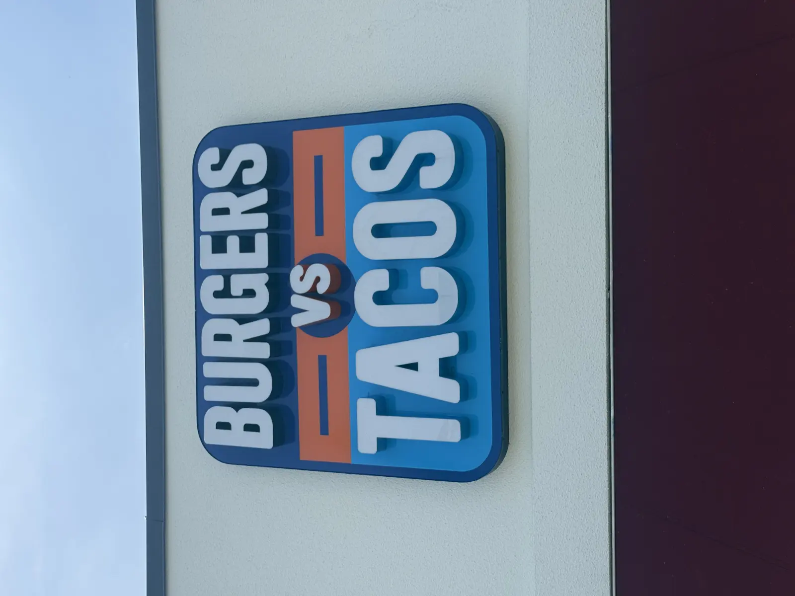 Official blue Burgers vs Tacos sign with the orange VS