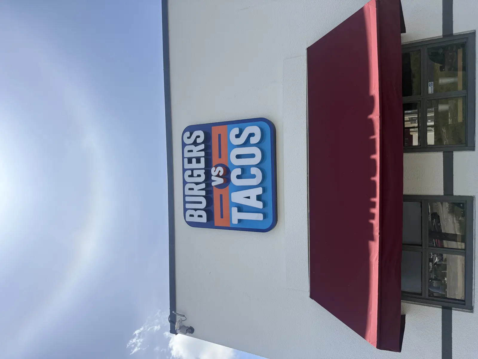 Burgers vs Tacos sign above the wine-colored entrance awning