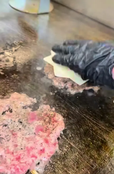 Smash patty with American cheese melting on the griddle