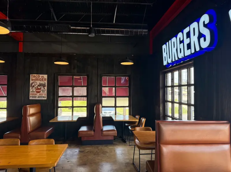 Dining room with brown leather booths and a neon sign