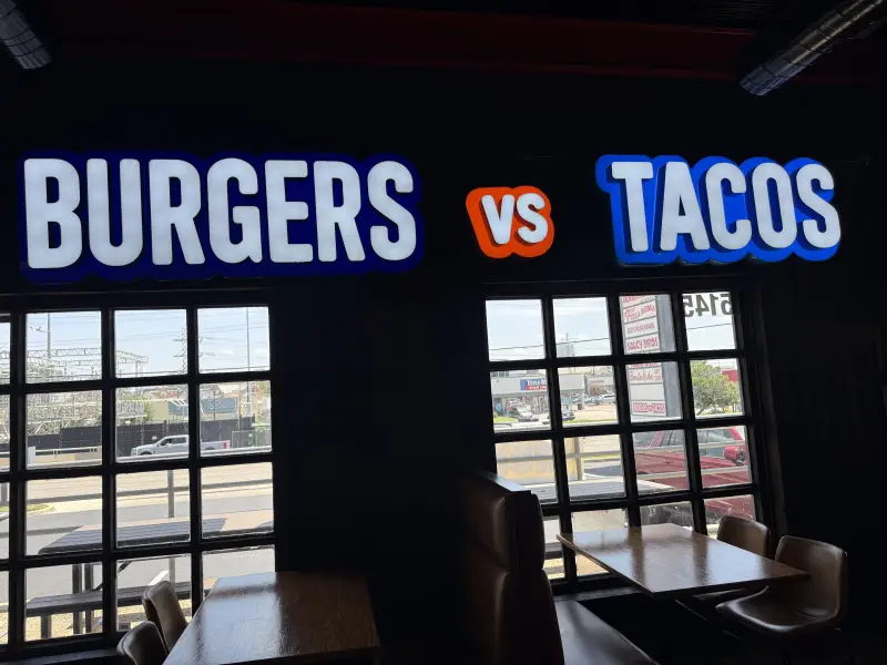 Close-up of the BURGERS VS TACOS neon sign